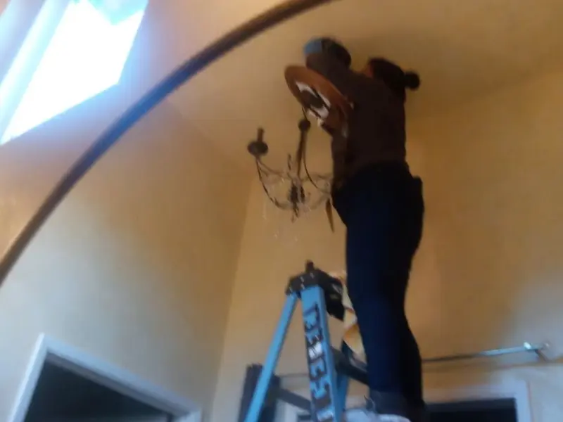 Electrician installing a chandelier in a Cooper residence